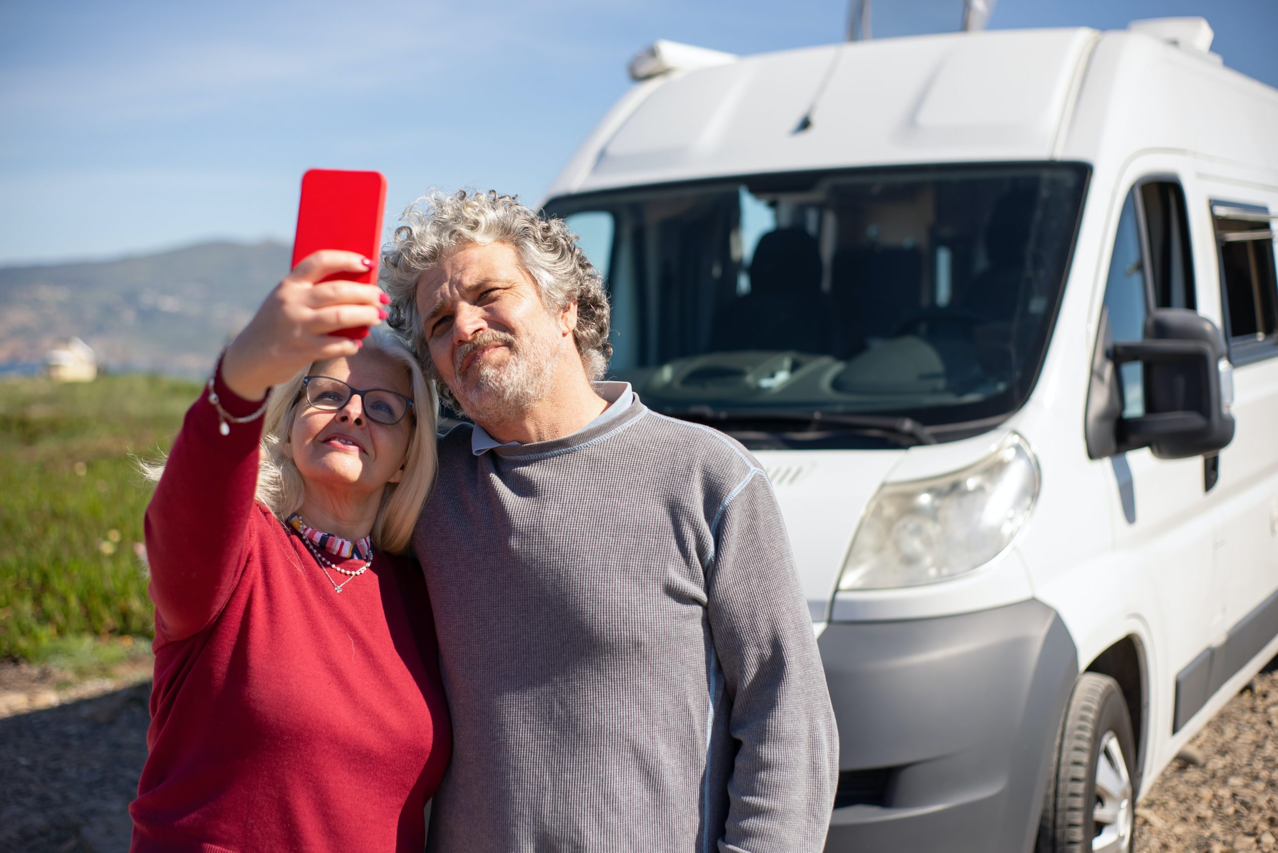 photo of couple taking a picture together in front of a caravan