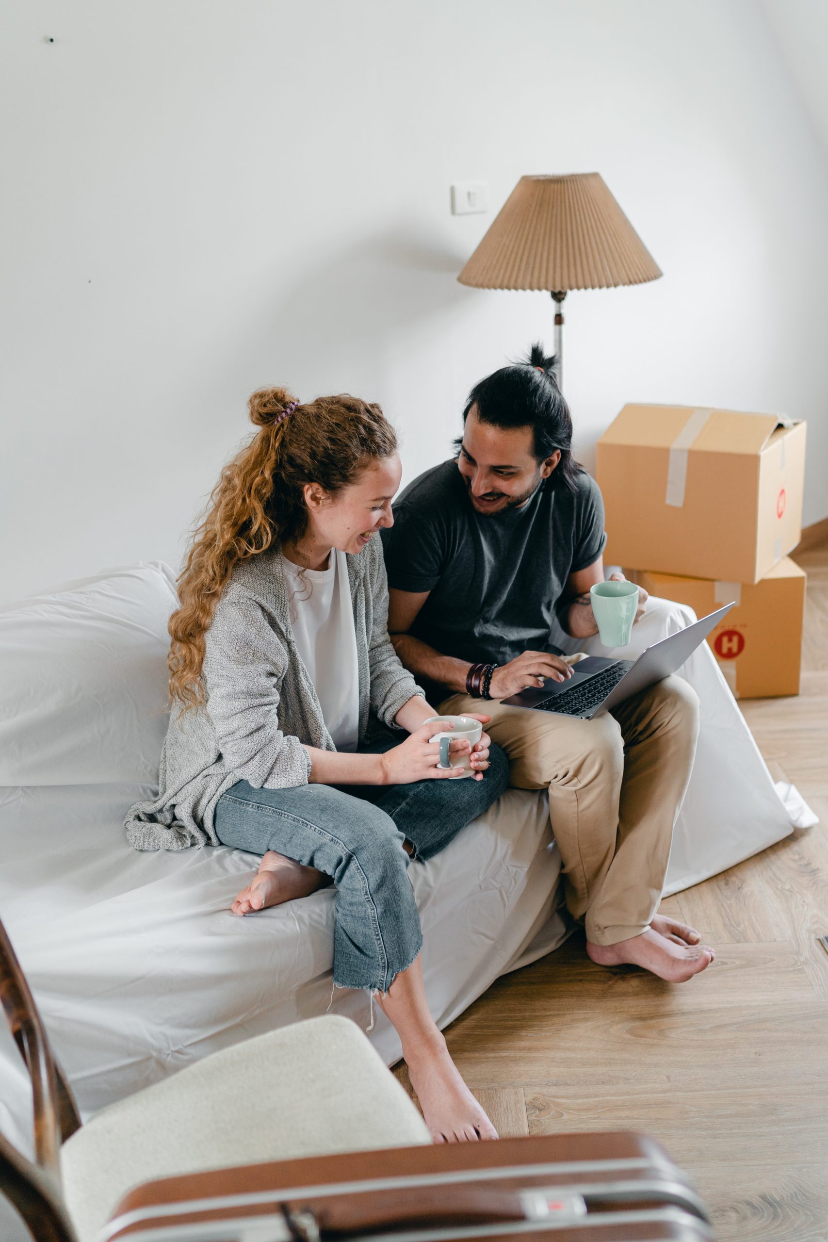 young couple sat in new house with boxes around them