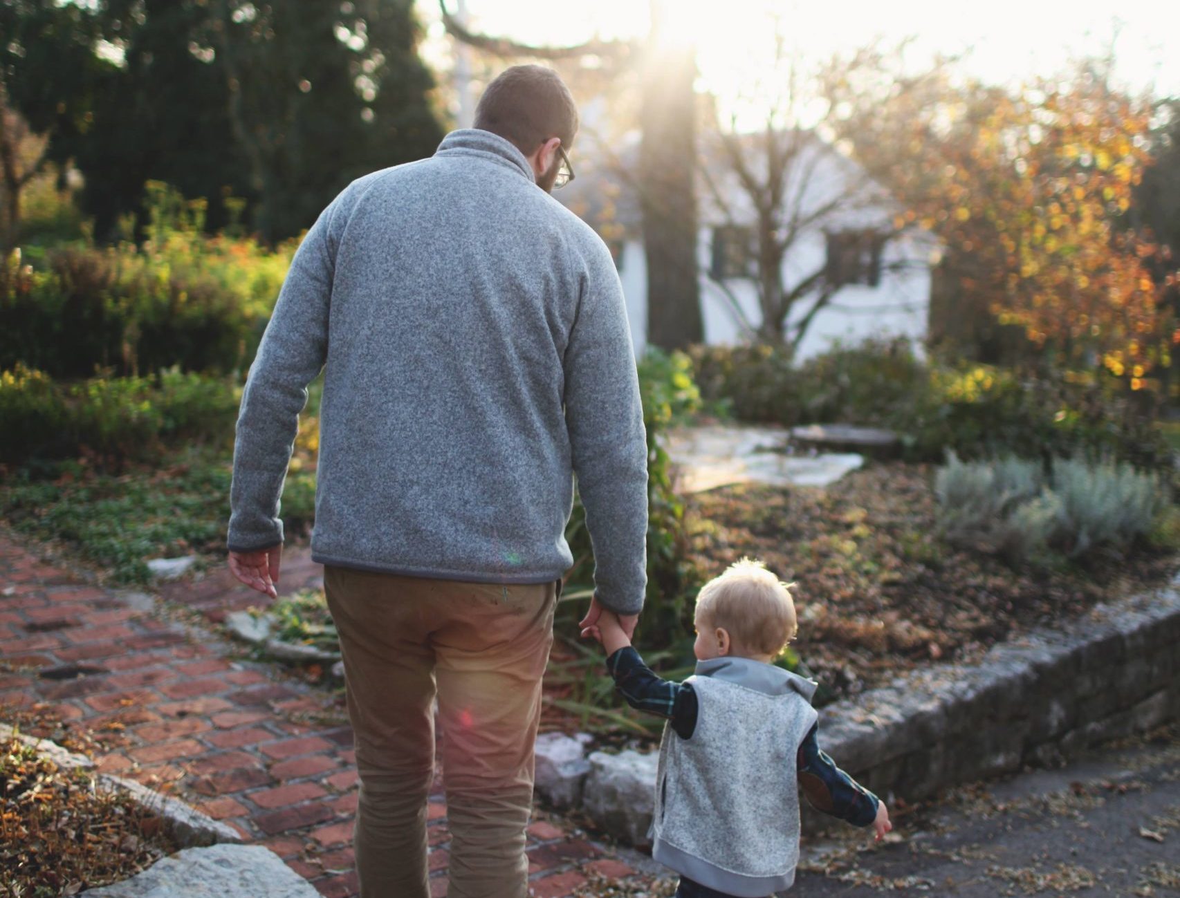 photo of father and boy walking holding hands